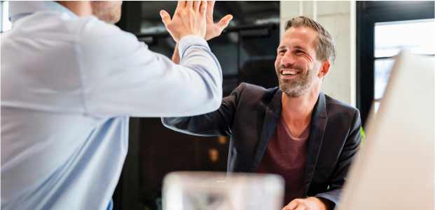 Two men giving each other a high five in a modern office.